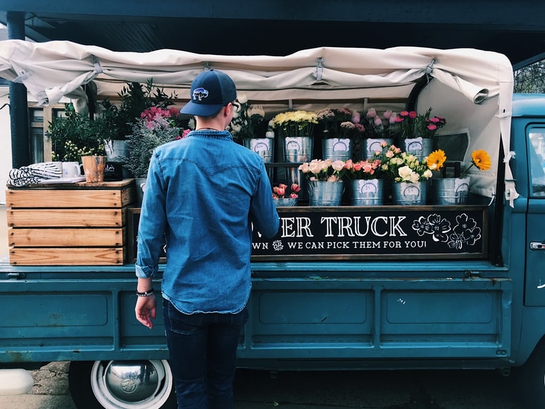 man standing in front of truck with flowers