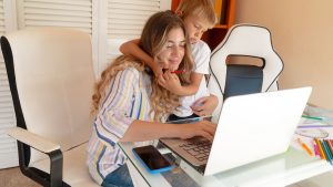 Image Alt Text: A mother working from her home business with her son – Merchant Growth