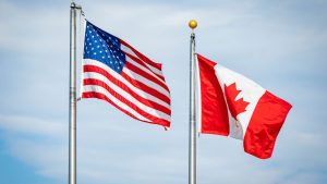 Canadian and American flag flying next to each other symbolizing the tariff impacts on cross-border purchases for small businesses